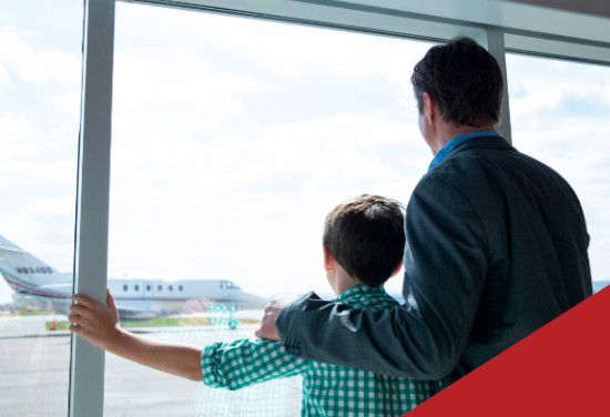 Man and boy looking out a large window at an airplane on the tarmac