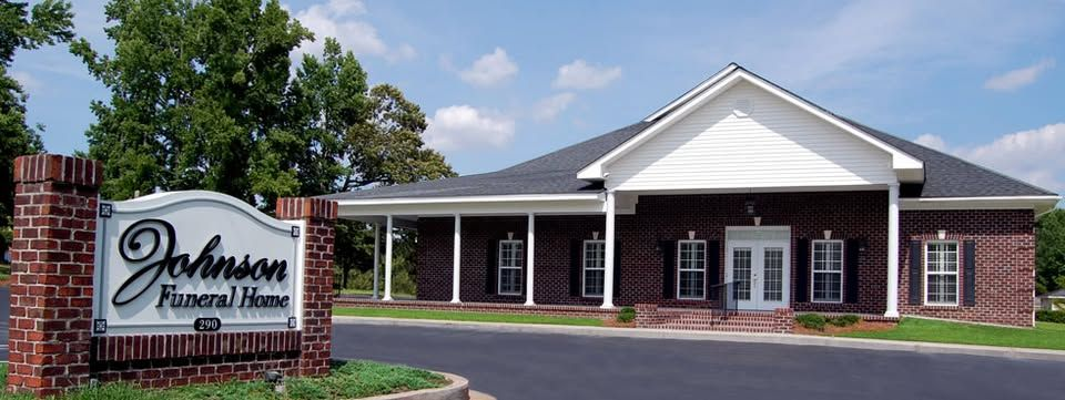 Johnson Funeral Home sign in front of a brick building with a porch and windows.