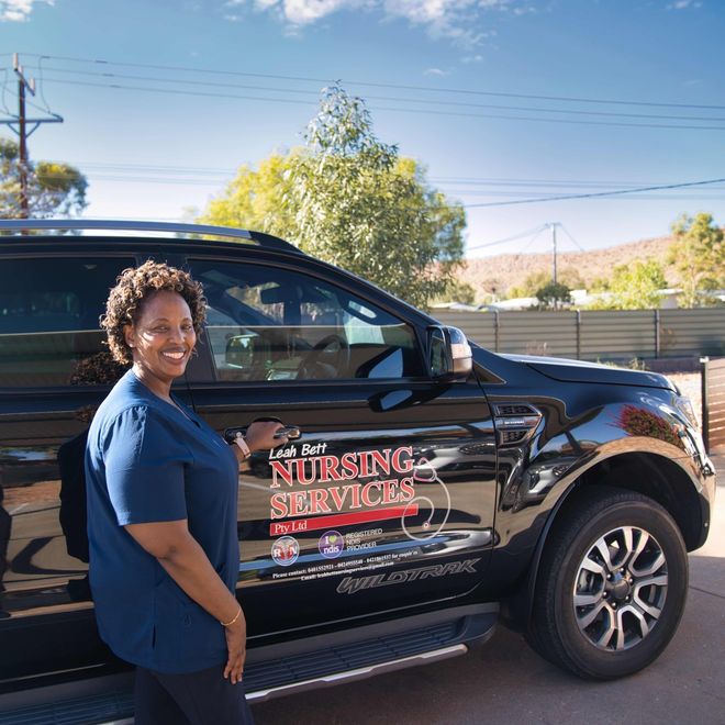 A woman is standing in front of a nursing services truck