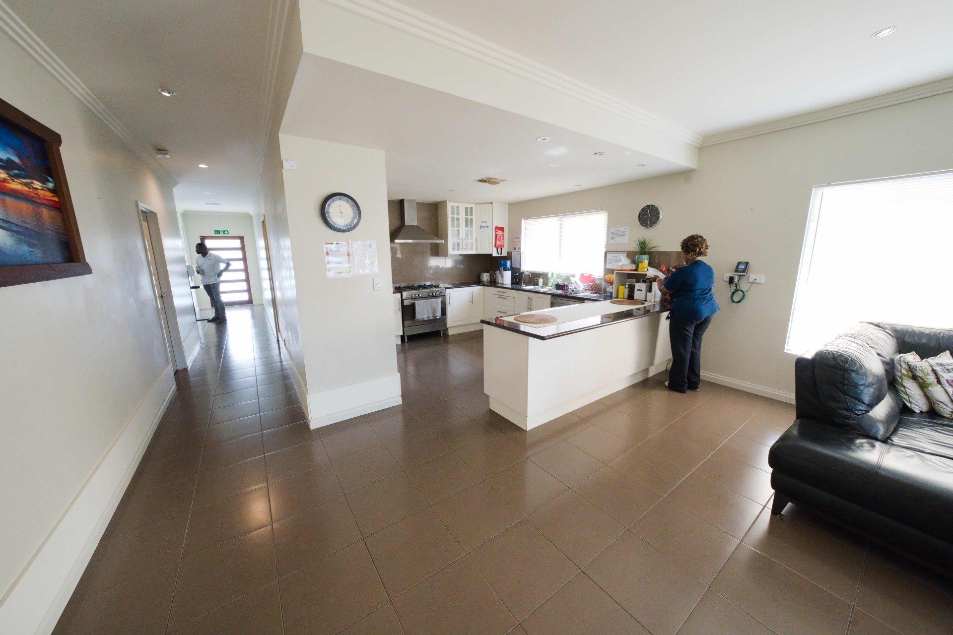 A woman is standing in a living room next to a kitchen.