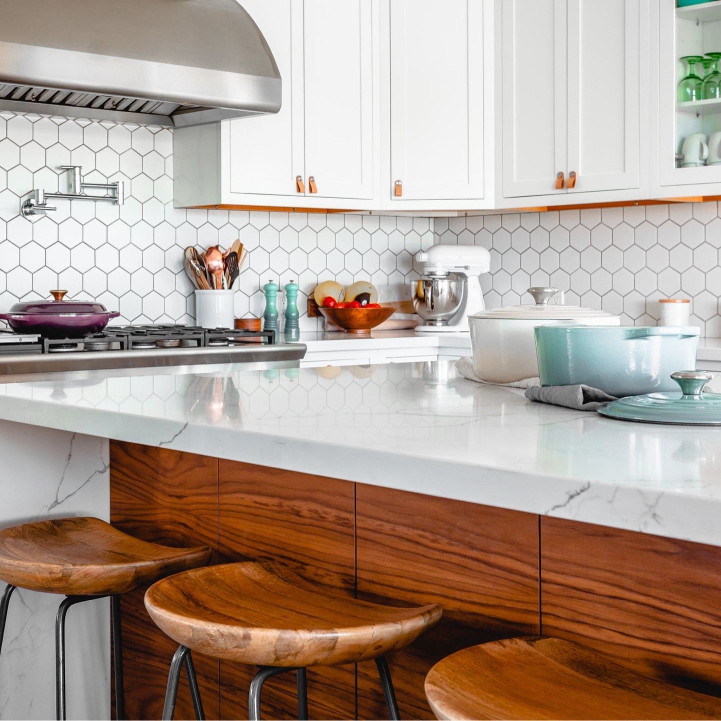 A kitchen with white cabinets and wooden stools