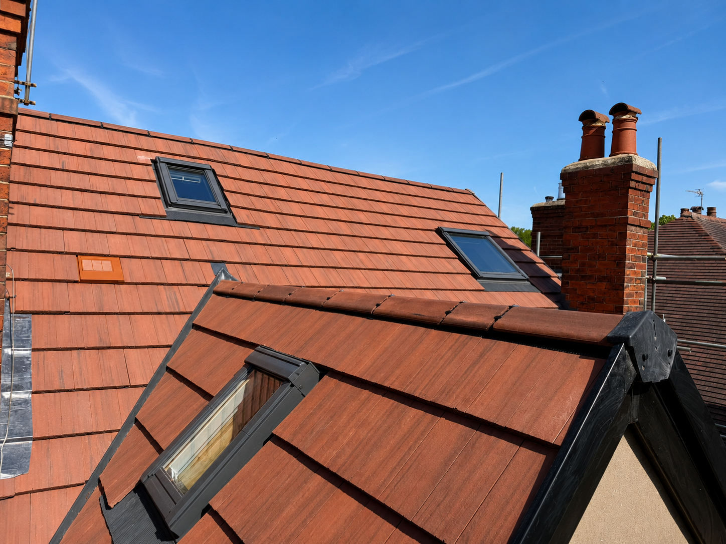 Red tiled rooftops with skylights under a clear blue sky