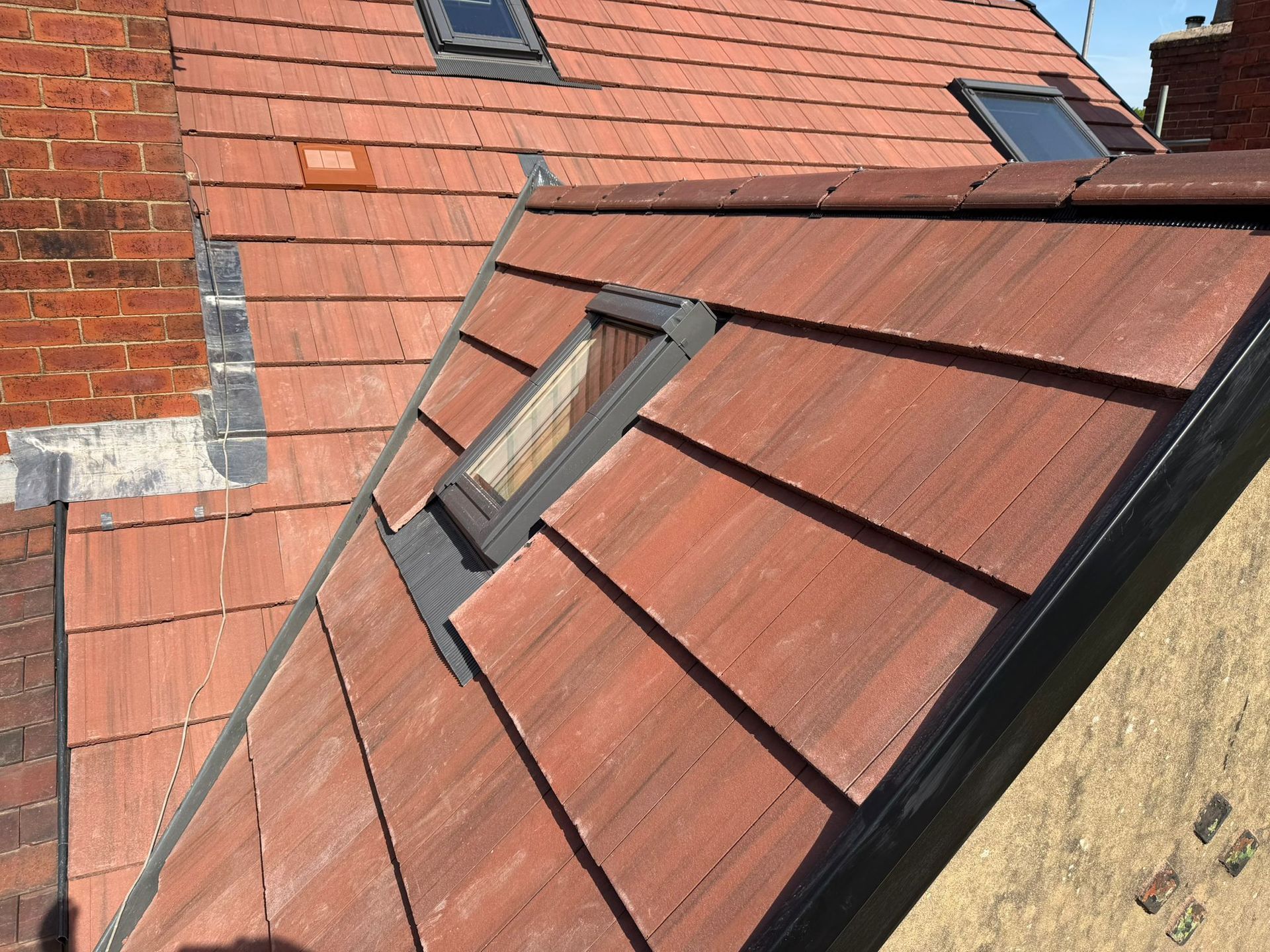 Close-up of a red-tiled roof with a skylight on a brick building