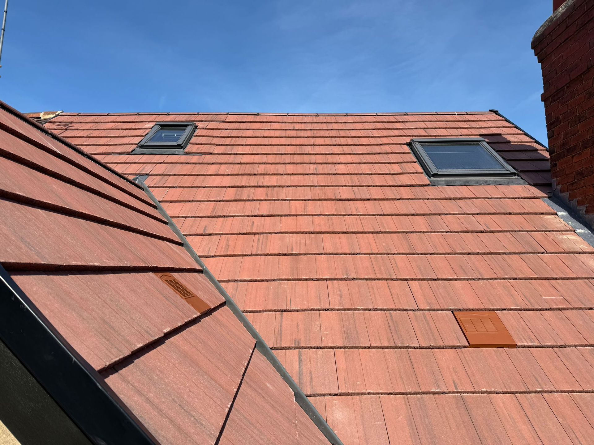 Red tiled rooftops with skylights against a blue sky