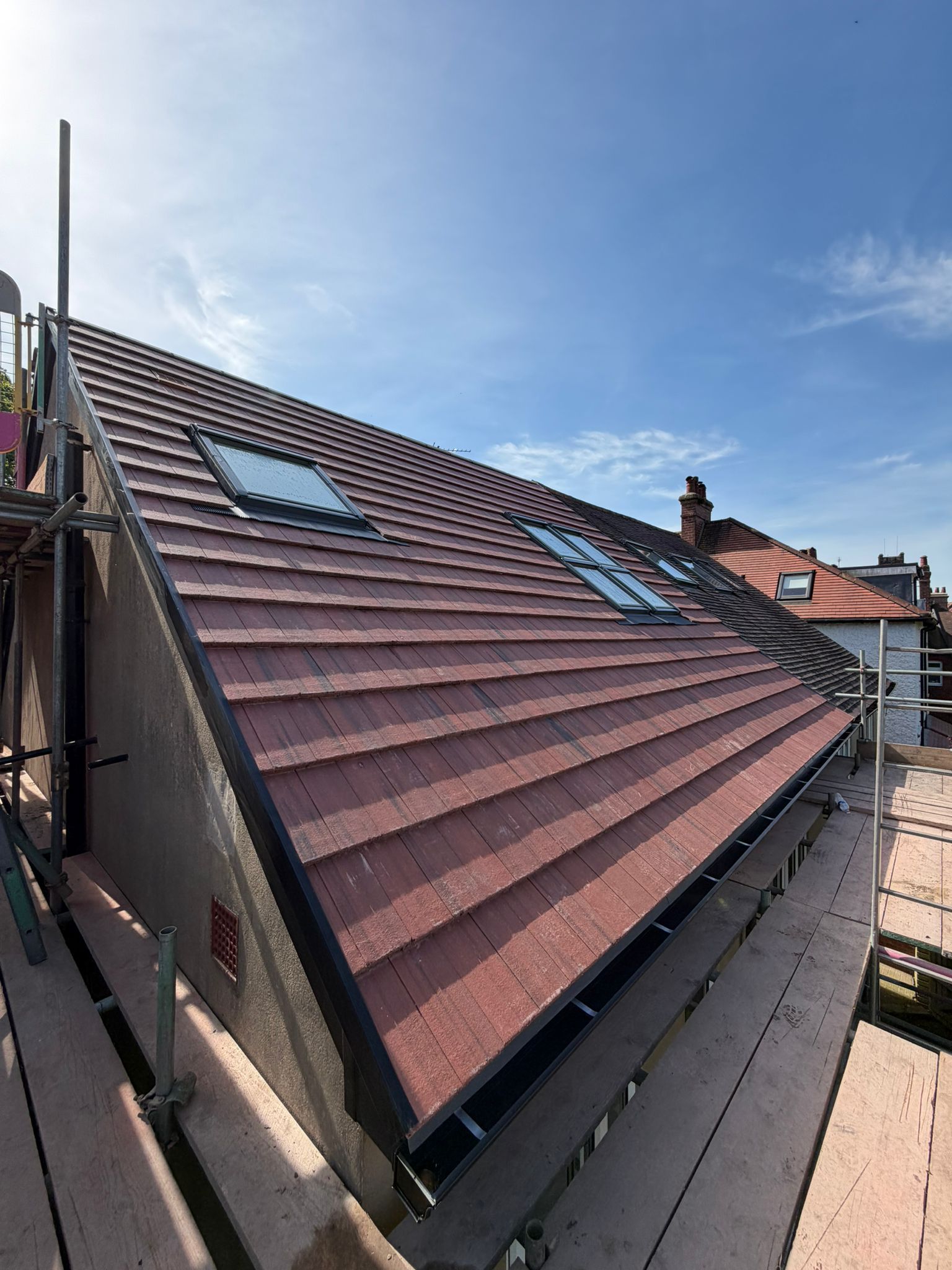 Rooftop with red tiles, skylight windows, and a blue sky on a sunny day