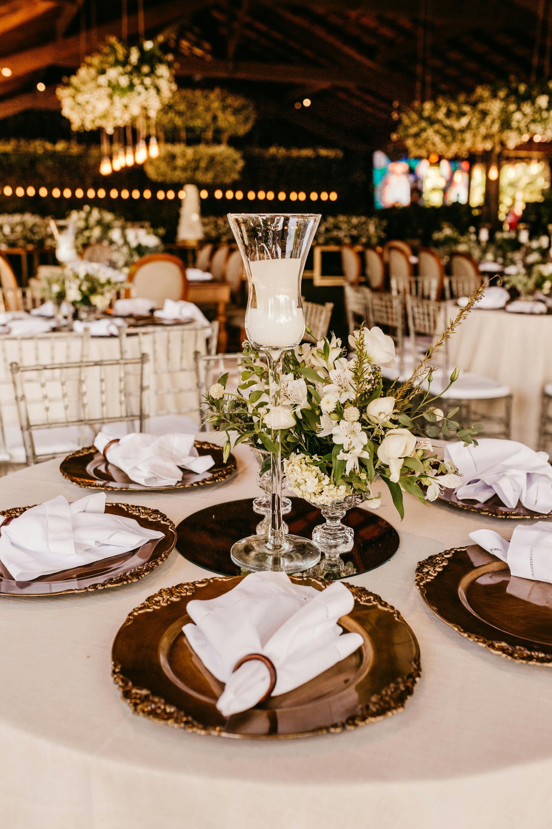 A table set for a wedding reception with plates , napkins , candles and flowers.