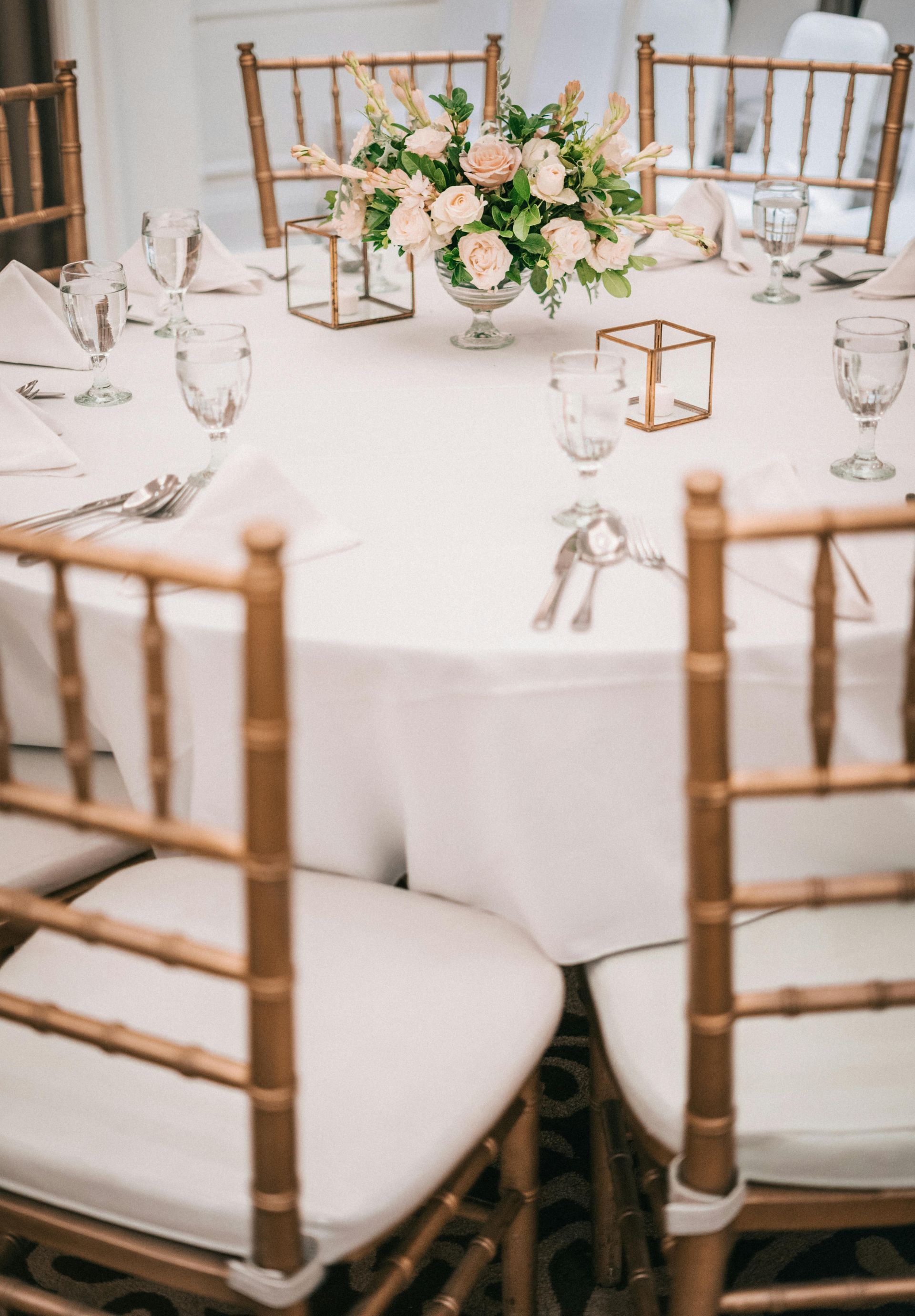 A table set for a wedding reception with a vase of flowers on it.