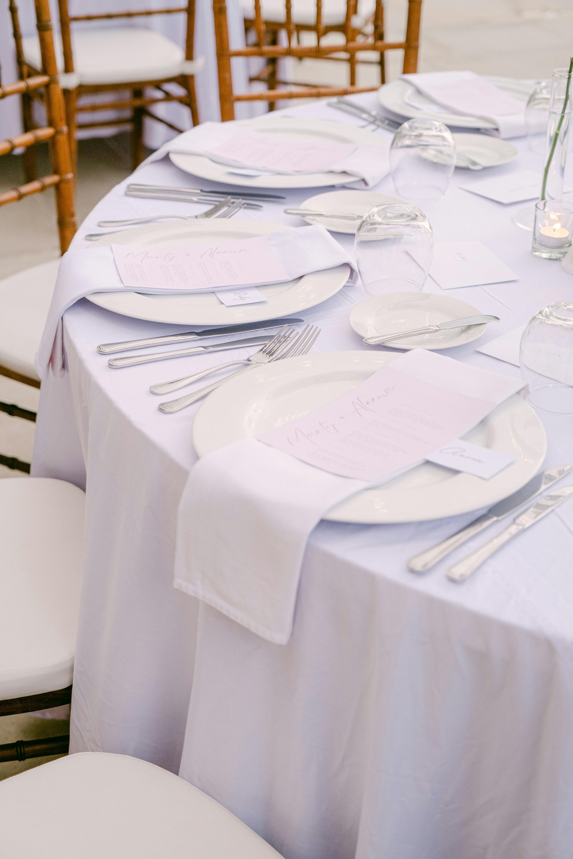 A round table with white plates , silverware , and napkins on it.