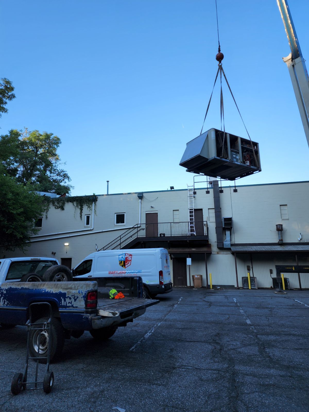 A crane is lifting a box over a truck in a parking lot