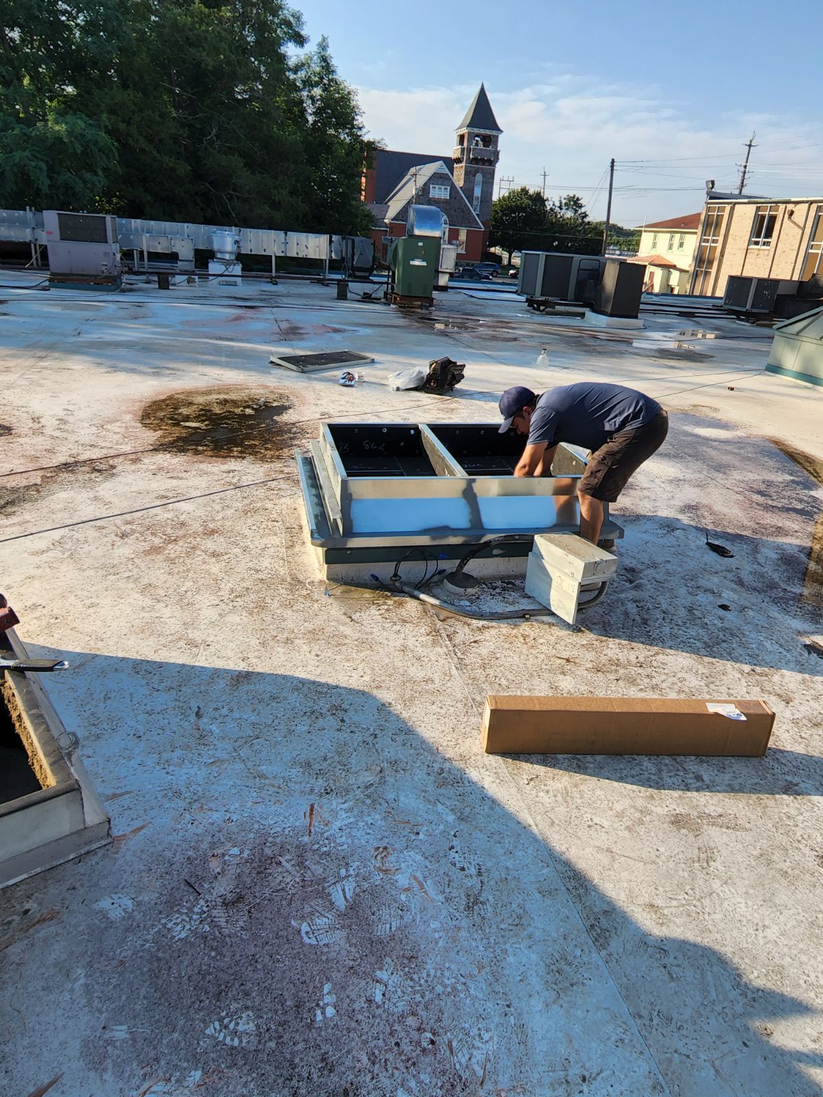 A man is working on a roof with a box in the foreground.