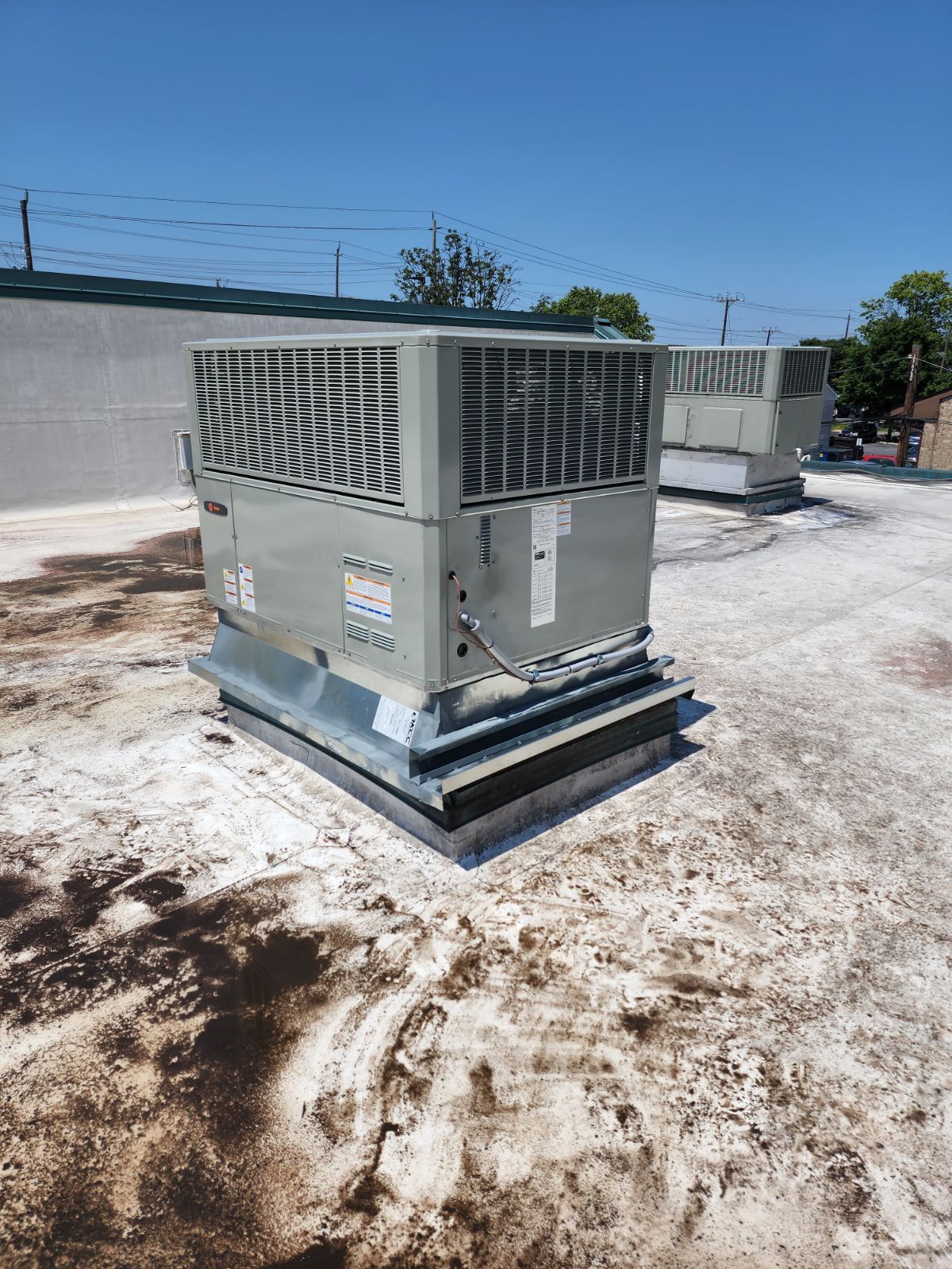 A large air conditioner is sitting on top of a dirty roof.