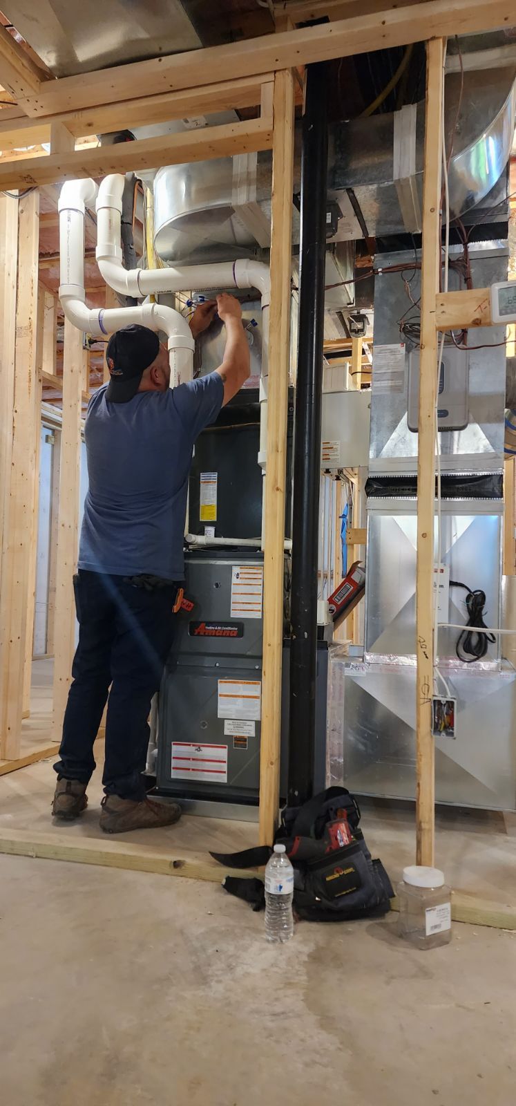 A man is working on an air conditioner in a basement.