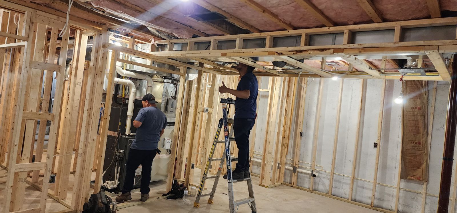 Two men are working in a basement under construction.
