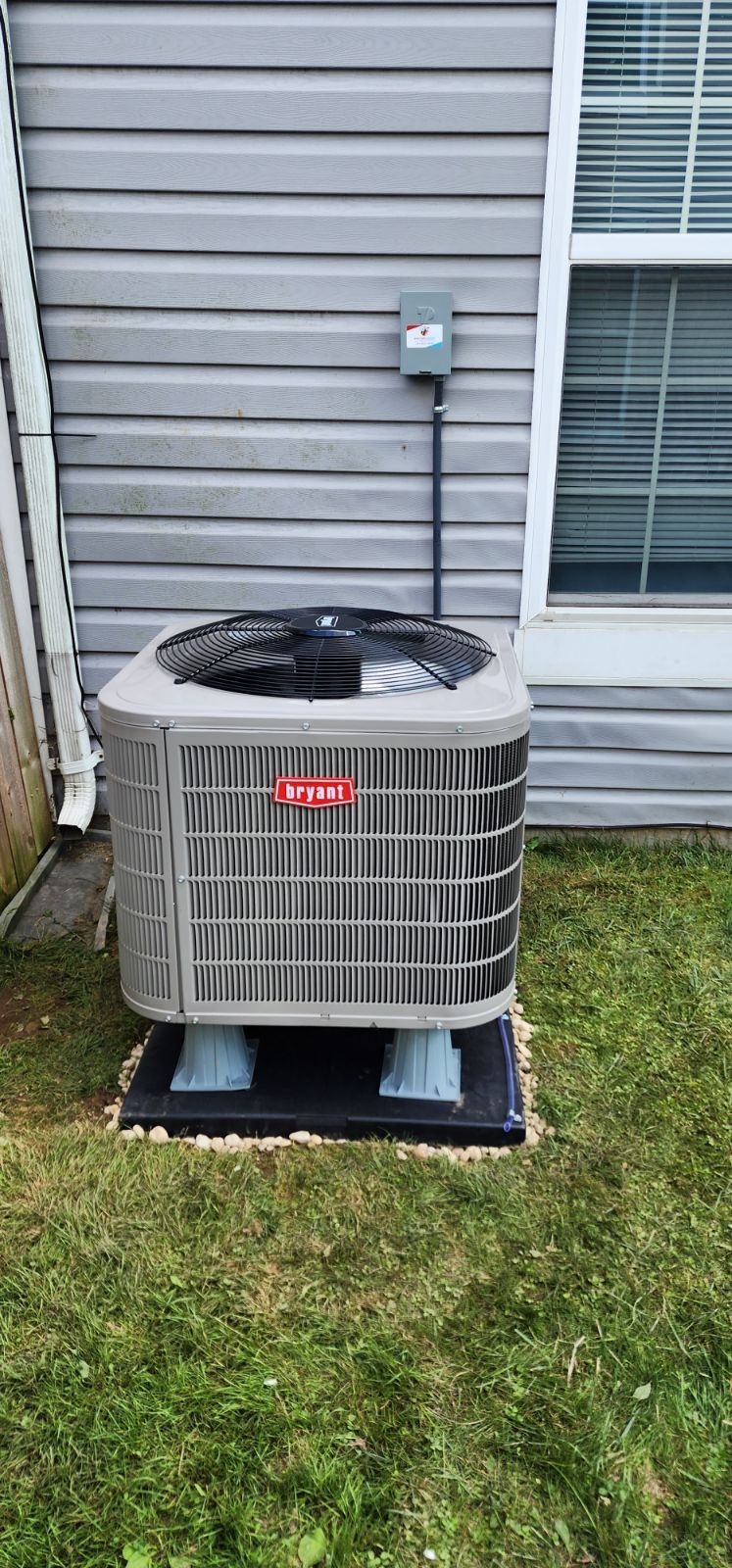 An air conditioner is sitting in the backyard of a house.