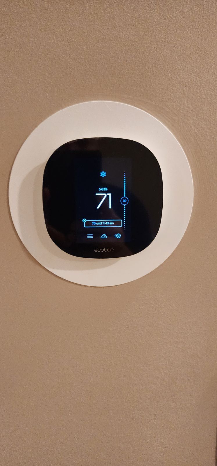 A smart thermostat is hanging on a wall.
