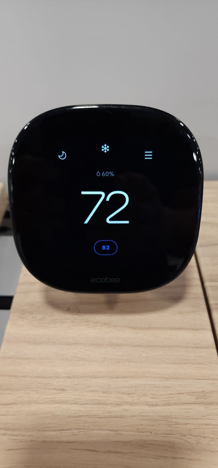 A smart thermostat is sitting on top of a wooden table.
