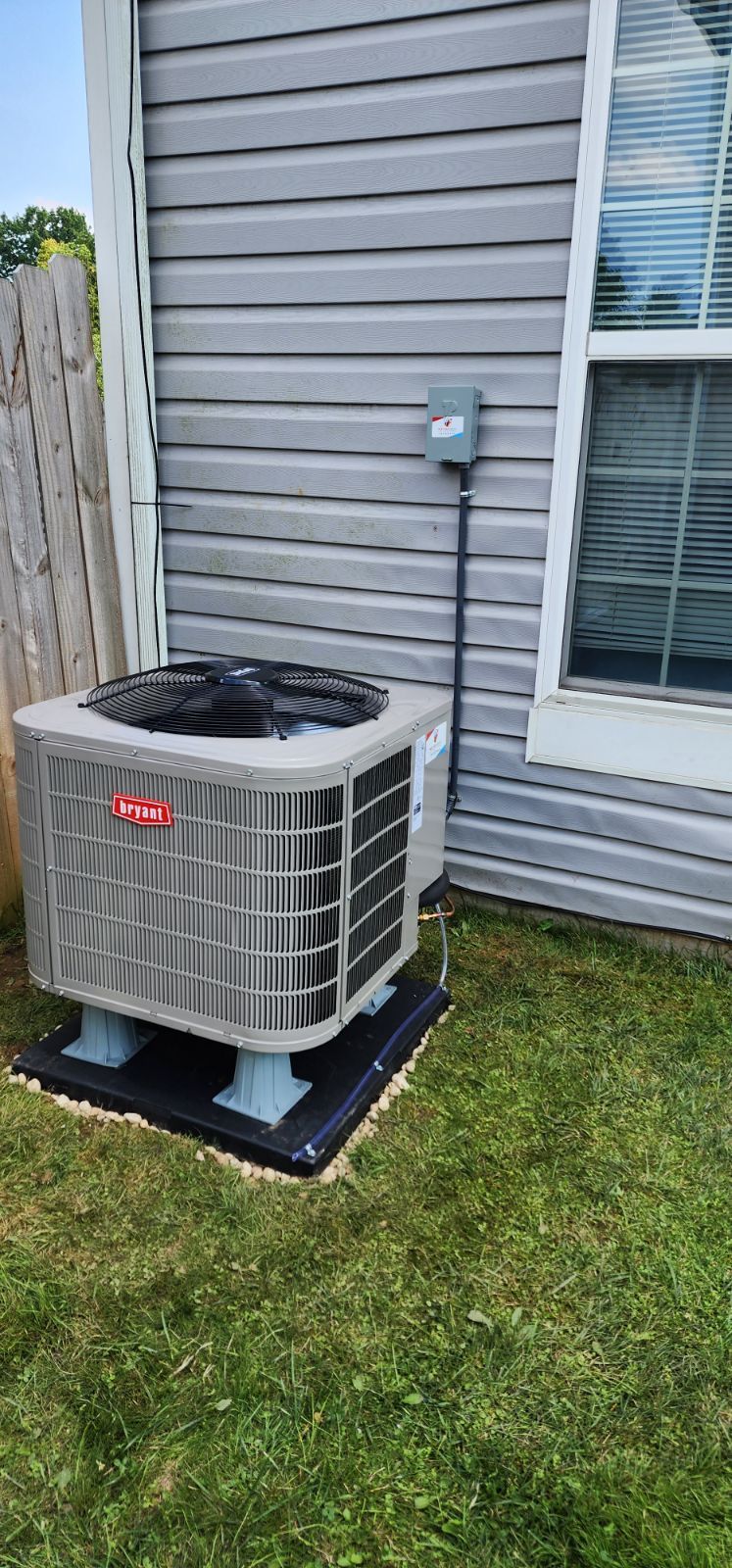 A large air conditioner is sitting in the grass next to a house.