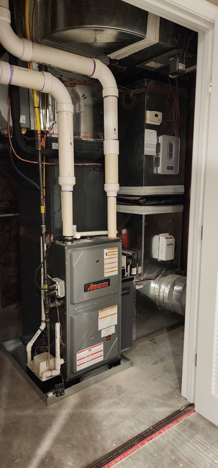 An air conditioner is sitting in a basement next to a door.