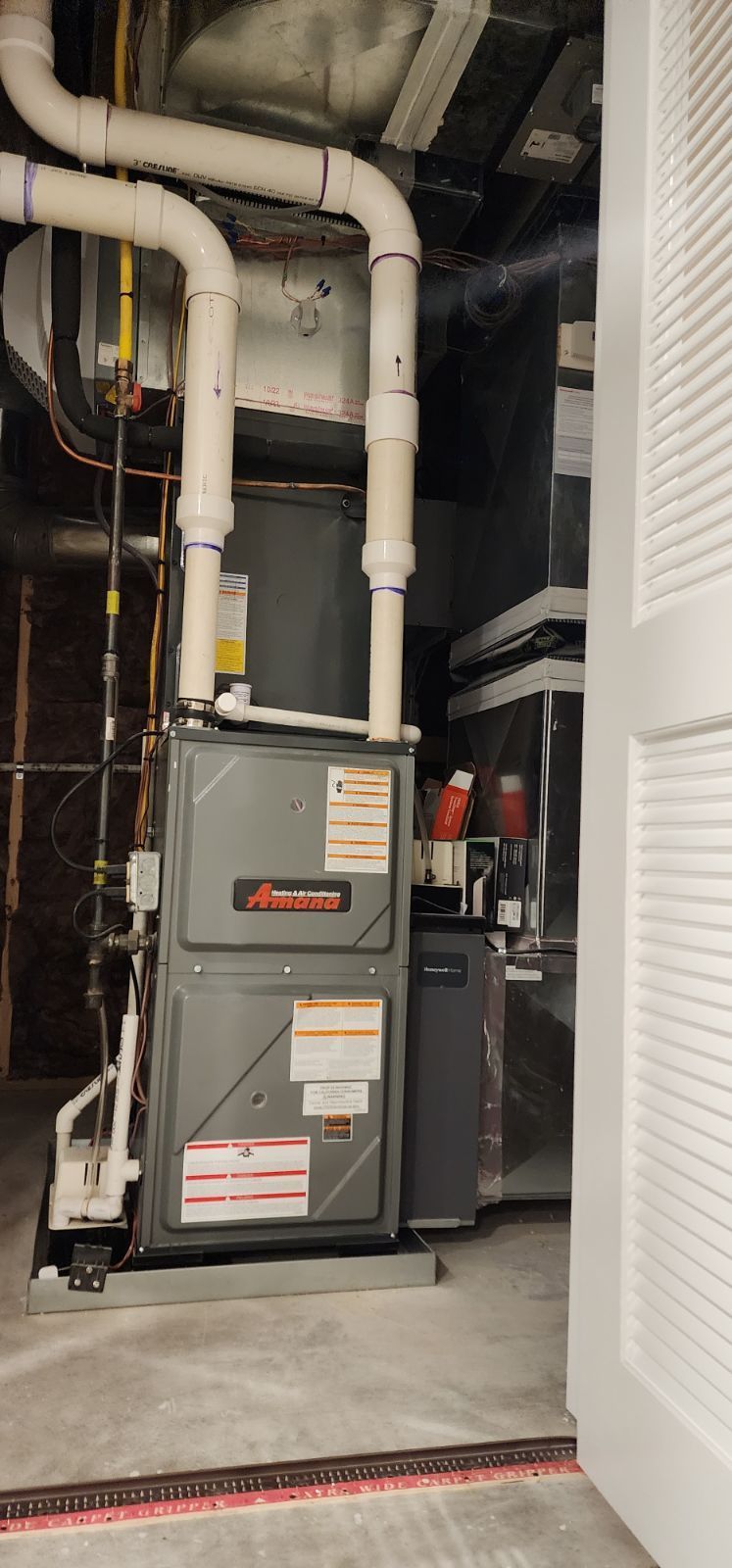 An air conditioner is sitting in a basement next to a door.