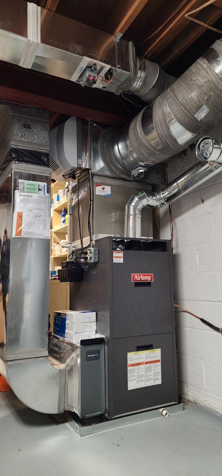 A large air conditioner is sitting in a basement next to a wall.