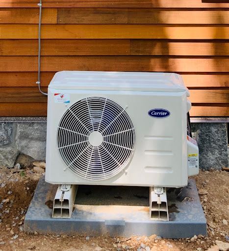 A carrier air conditioner is sitting outside of a house