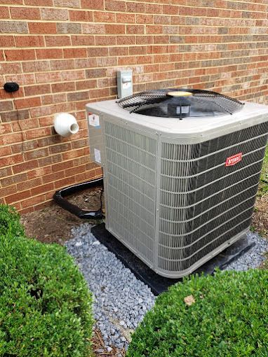 A large air conditioner is sitting outside of a brick building.