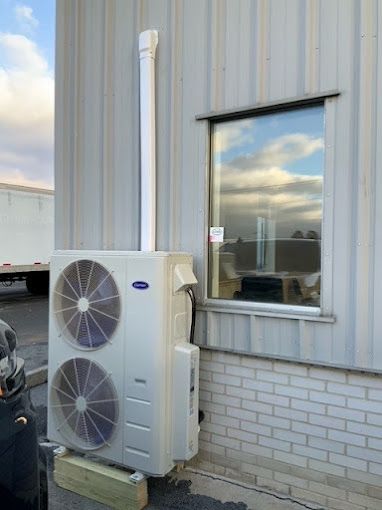 A large air conditioner is mounted on the side of a building next to a window.