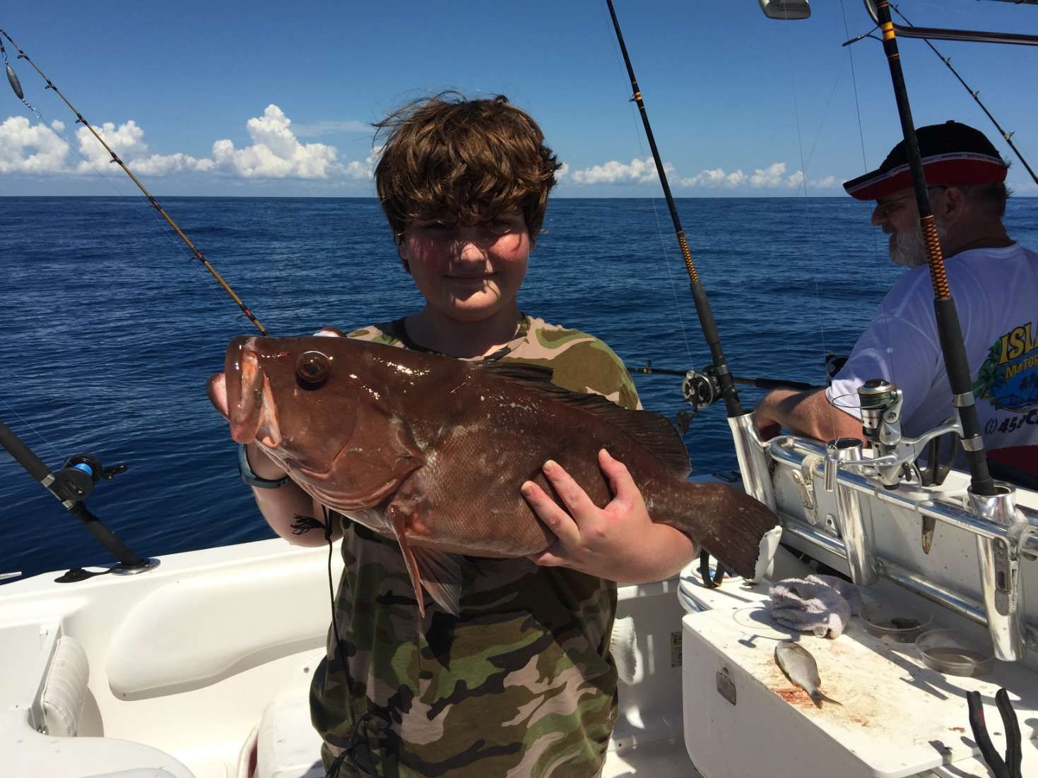 A young boy is holding a large fish on a boat.