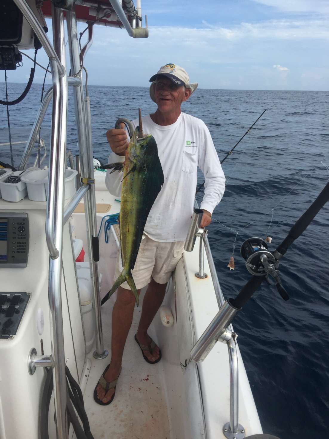 A man is holding a fish on a boat in the ocean.