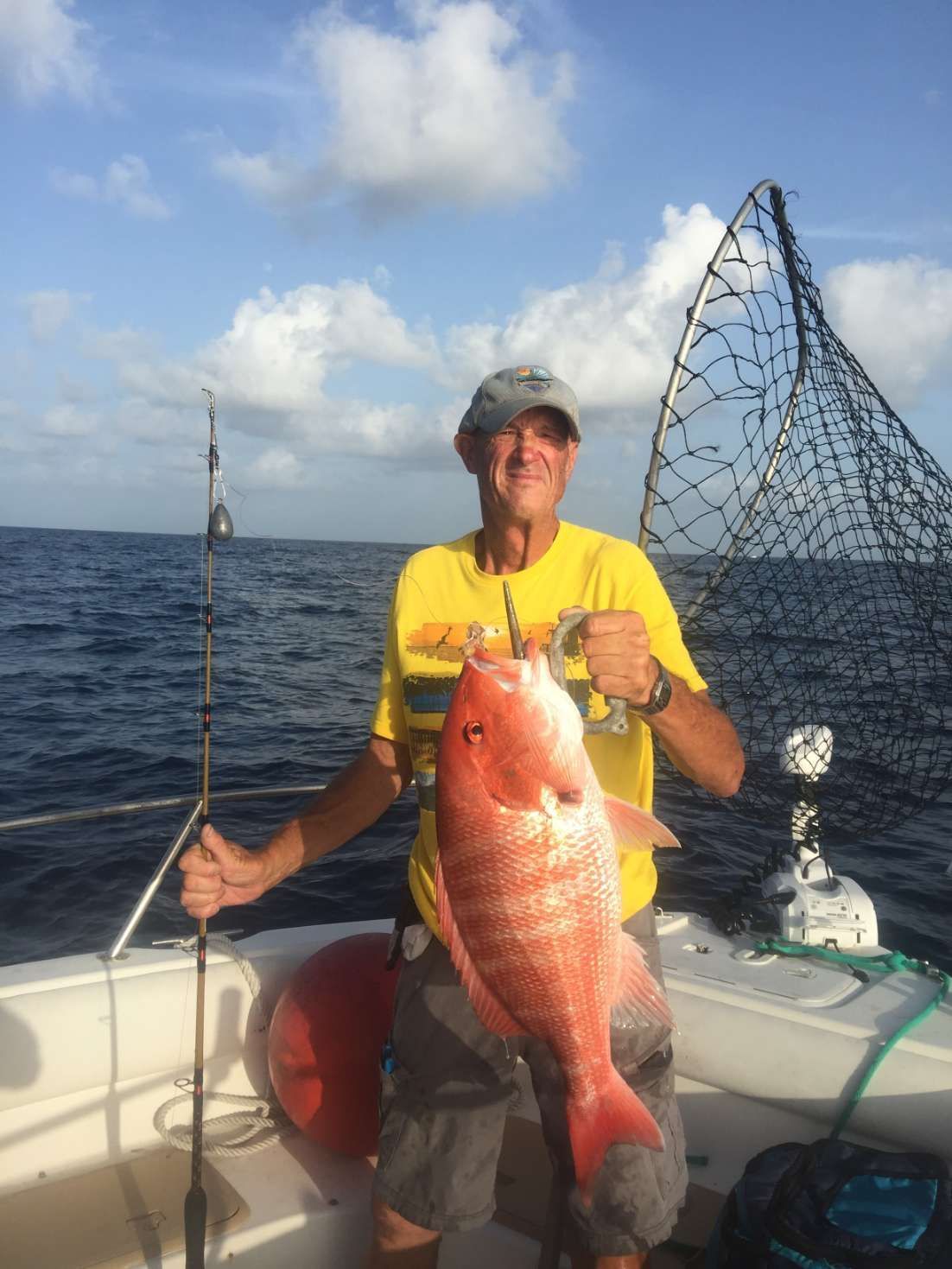 A man is holding a large red fish on a boat.
