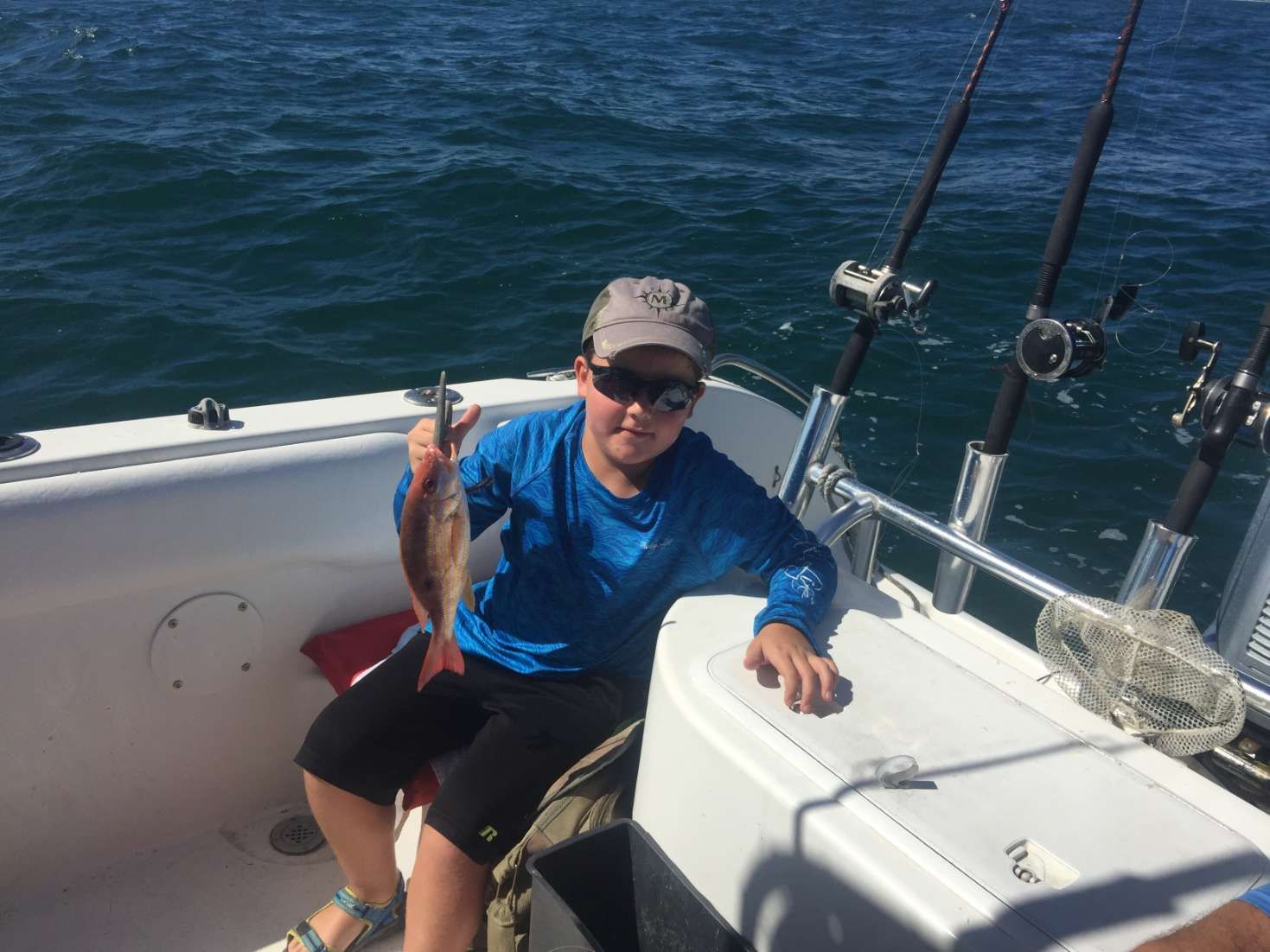 A young boy is sitting on a boat holding a fish.