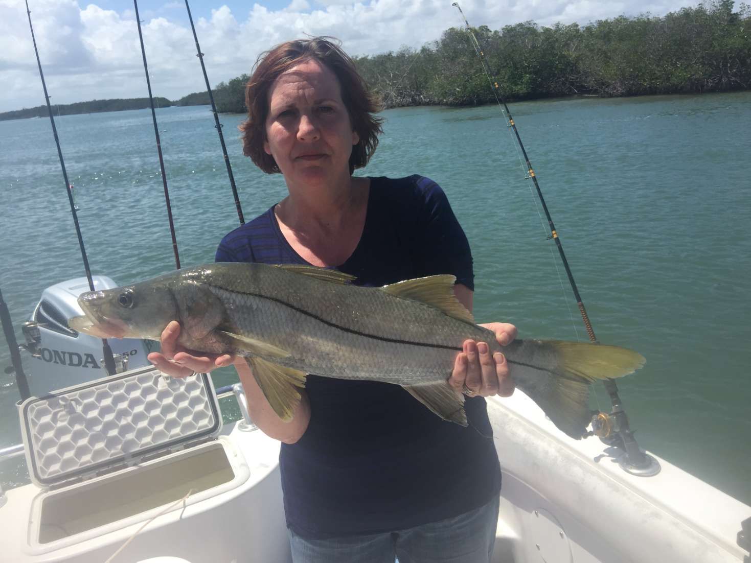 A woman is holding a large fish on a boat.