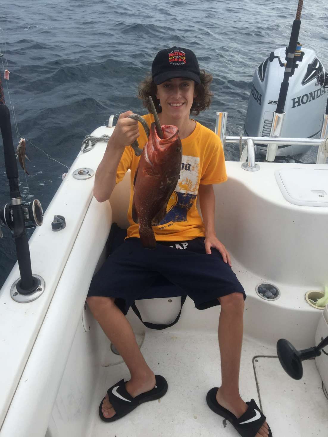 A young boy is sitting on a boat holding a fish