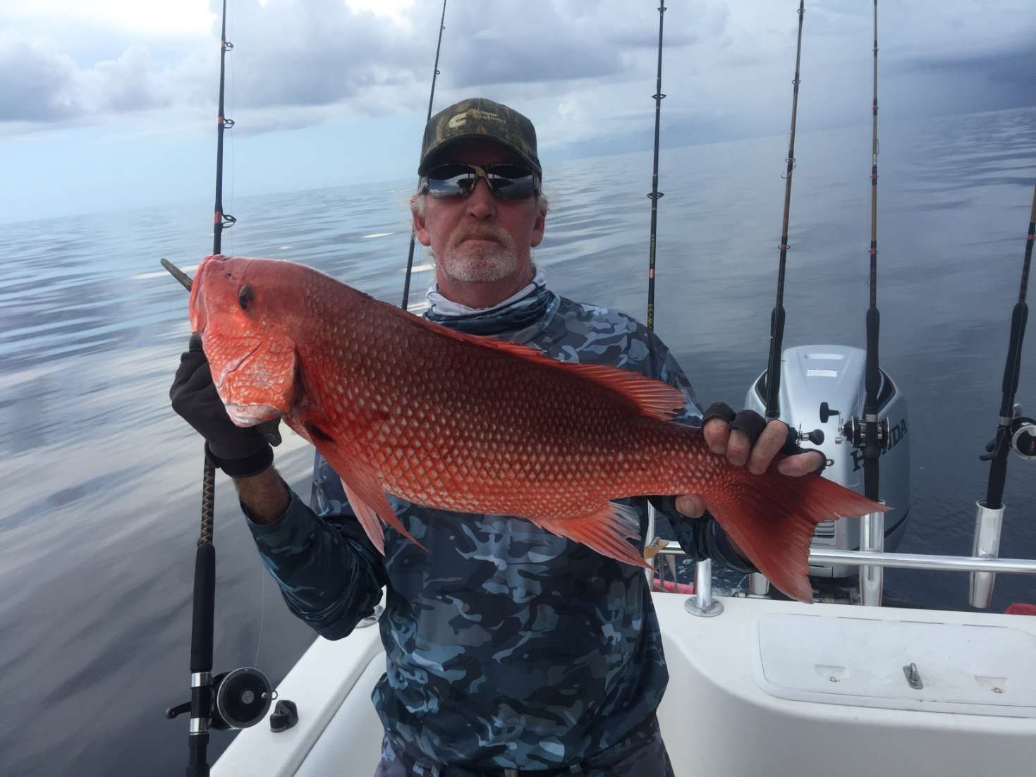 A man is holding a large red fish on a boat.