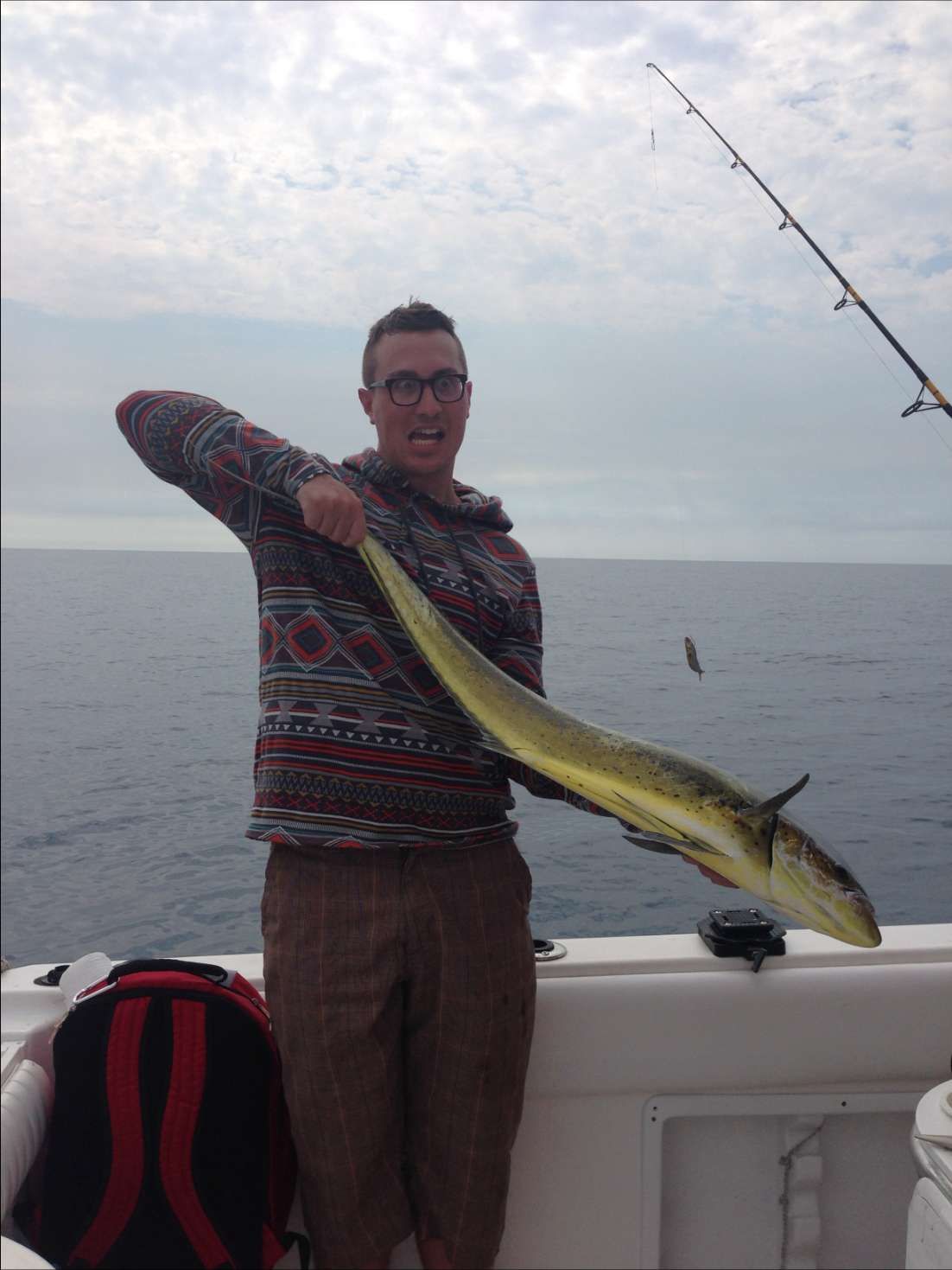 A man is holding a fish on a boat in the ocean
