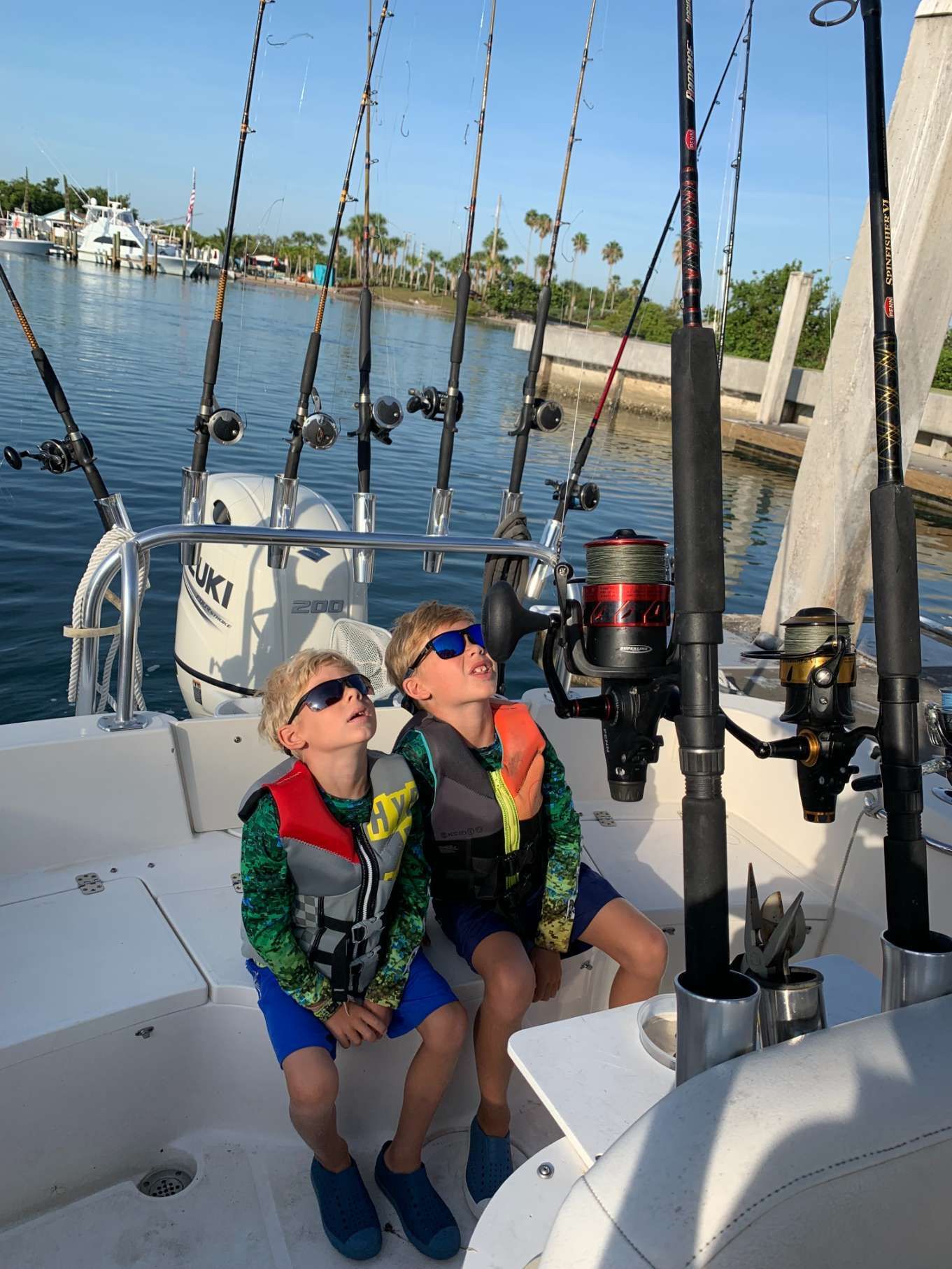 Two young boys are sitting on a boat looking up at the water.