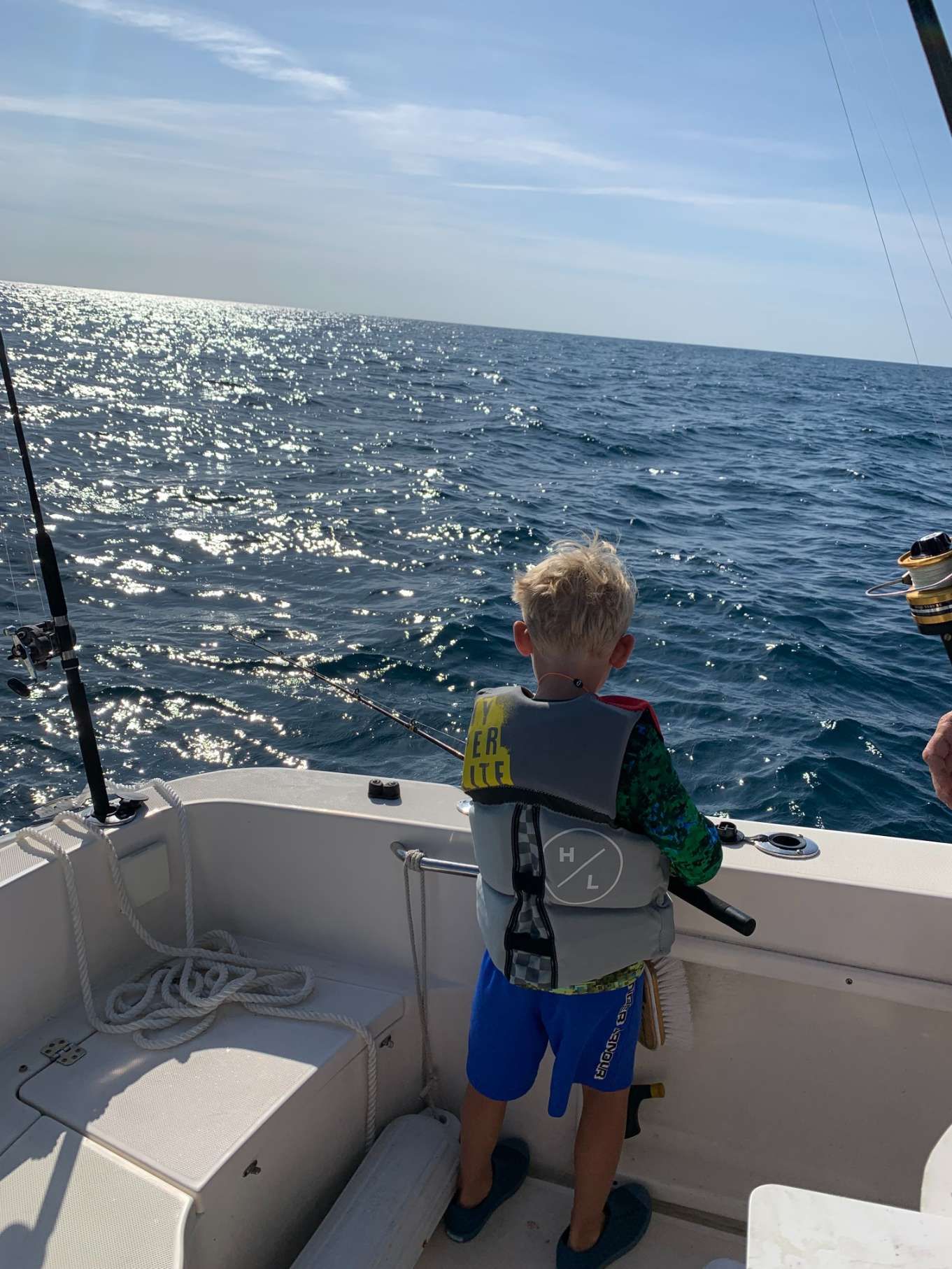 A young boy is fishing on a boat in the ocean.