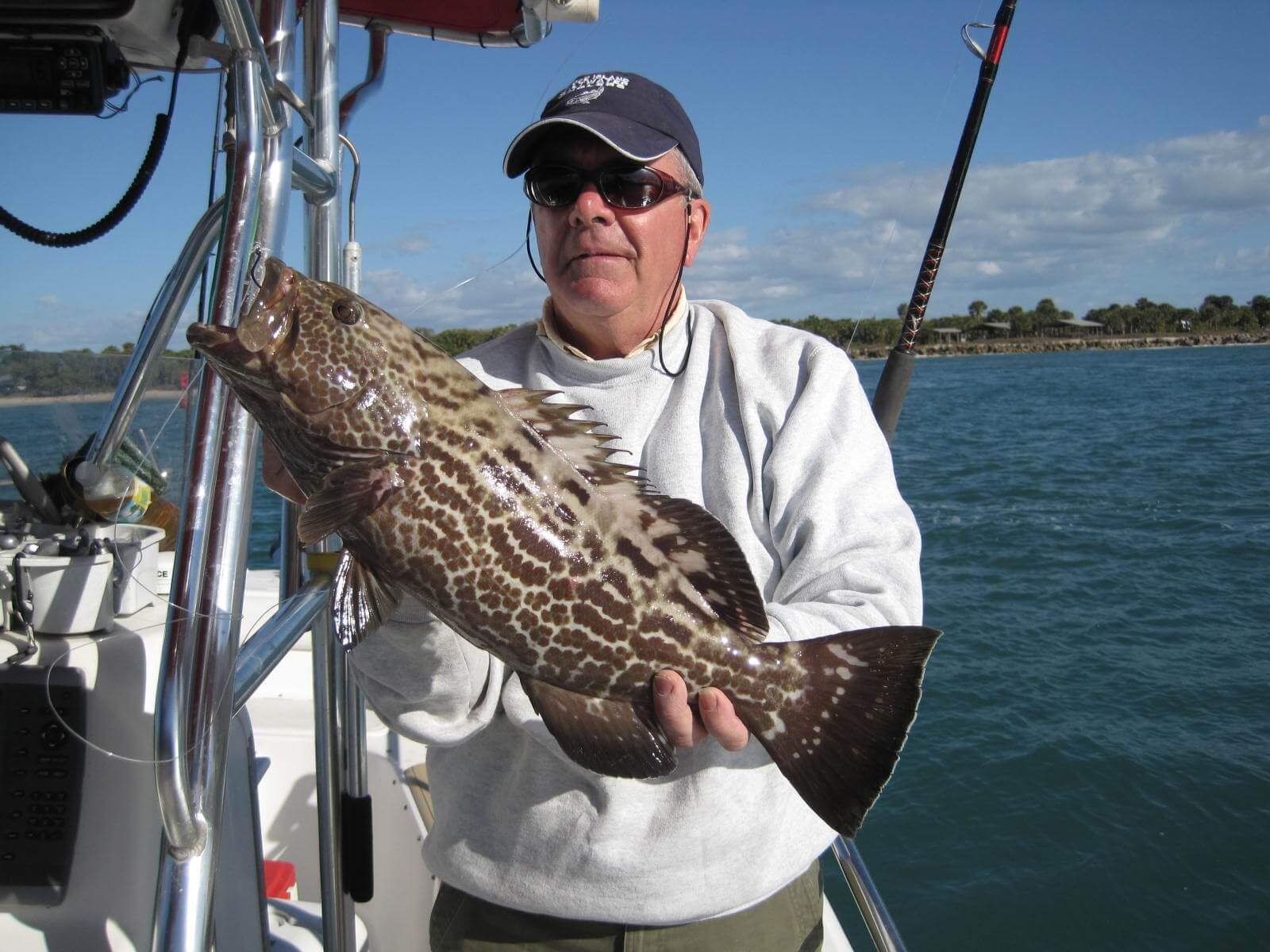 A man is holding a large fish on a boat