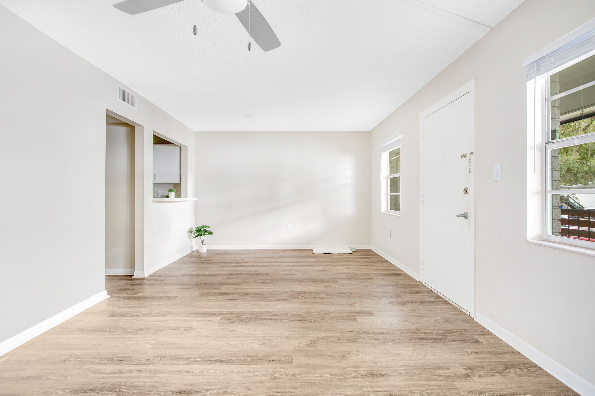 An empty living room with hardwood floors and a ceiling fan.