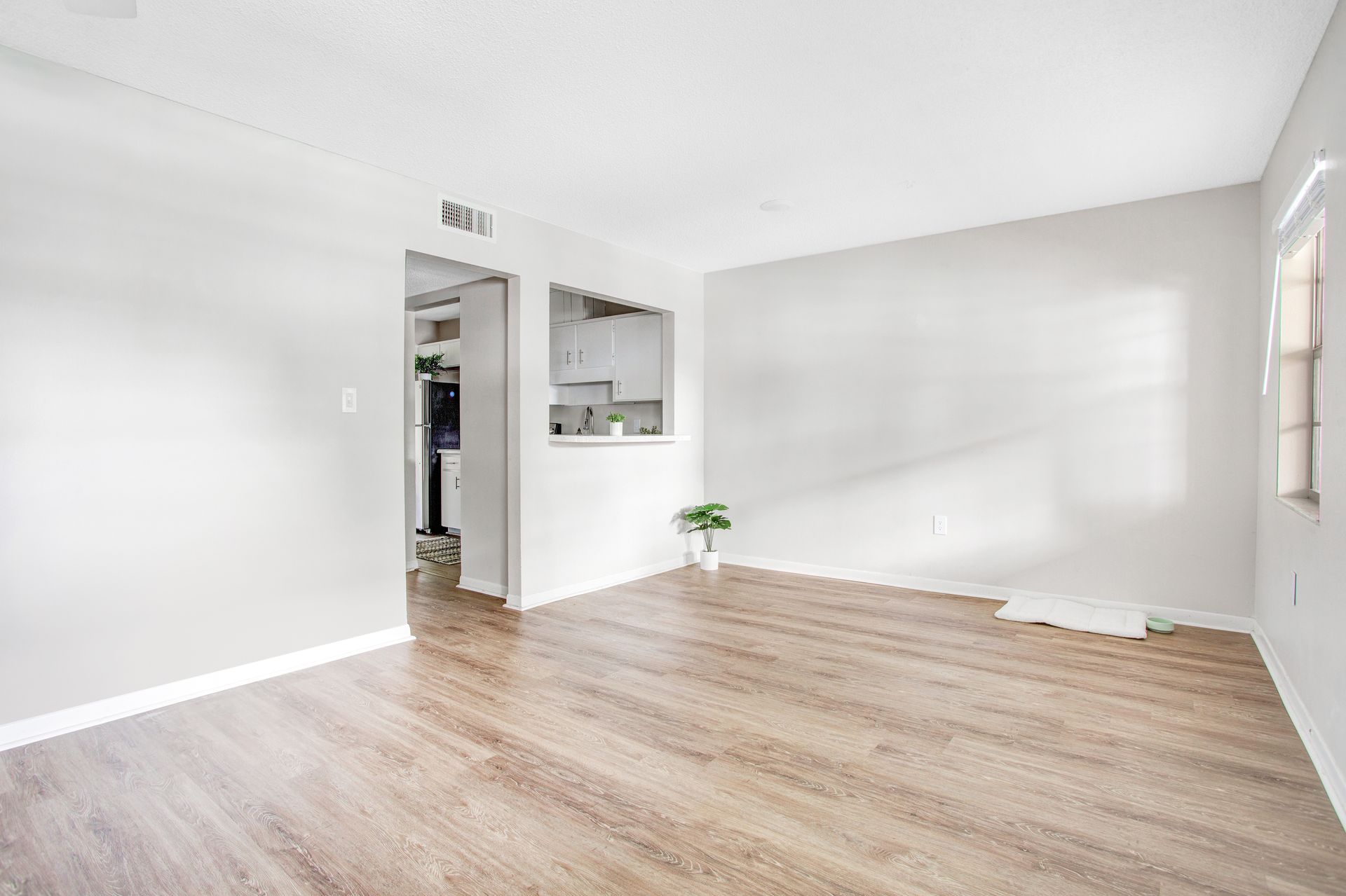 An empty living room with hardwood floors and white walls.