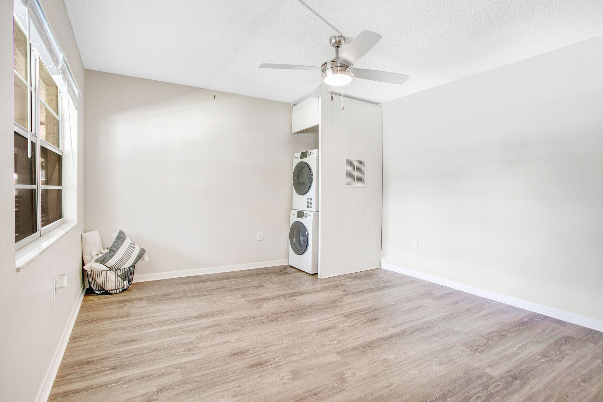 A living room with a washer and dryer stacked on top of each other.