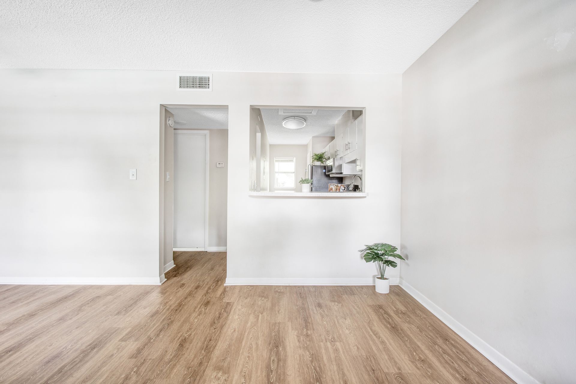 An empty living room with hardwood floors and white walls.