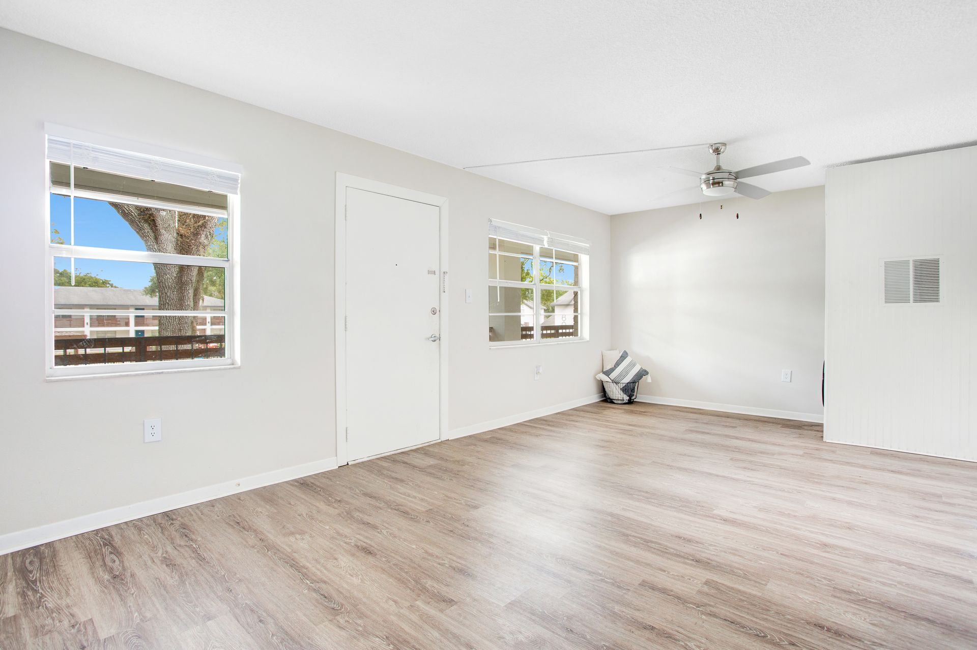 An empty living room with hardwood floors and a ceiling fan.