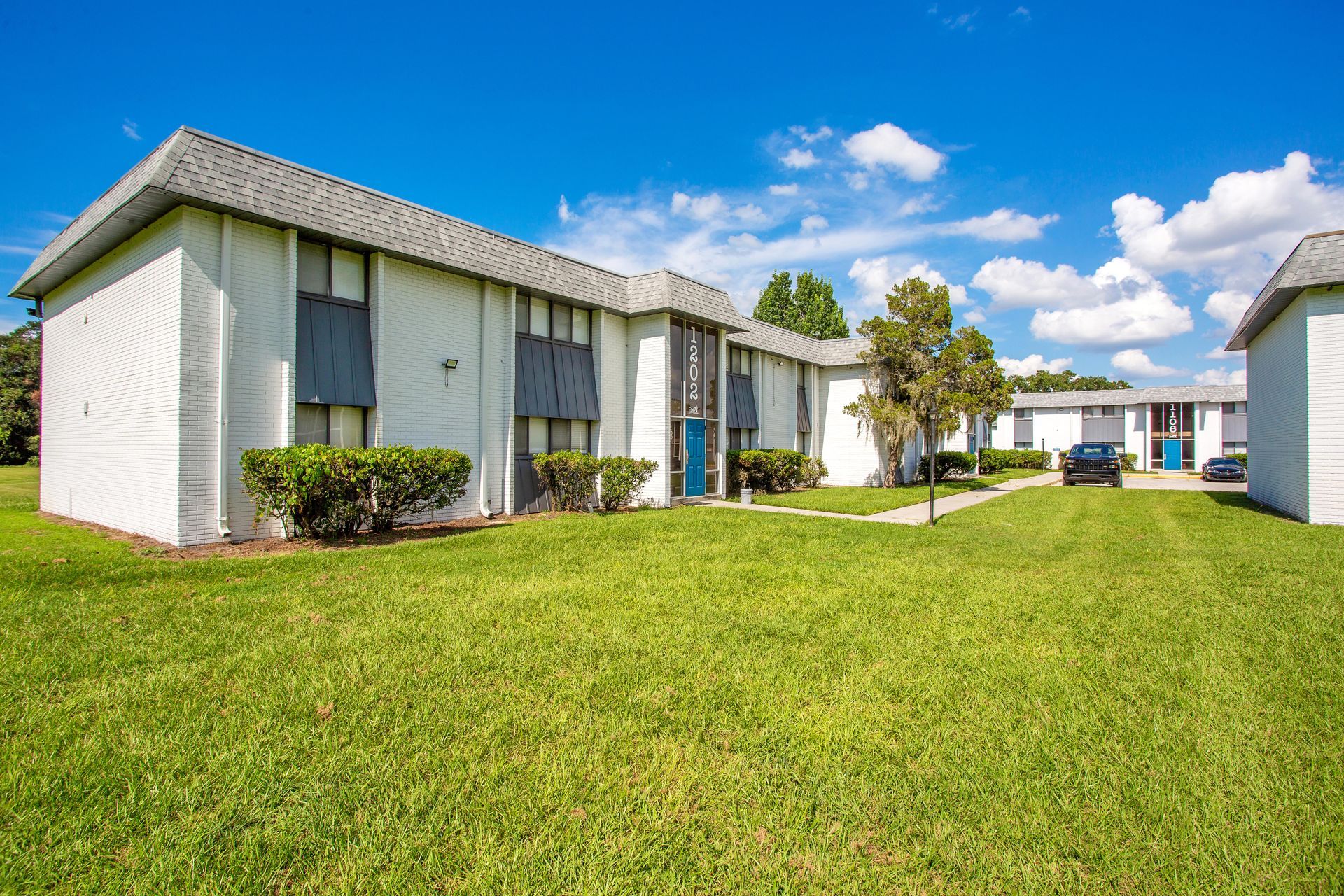A white apartment building with a lush green lawn in front of it.