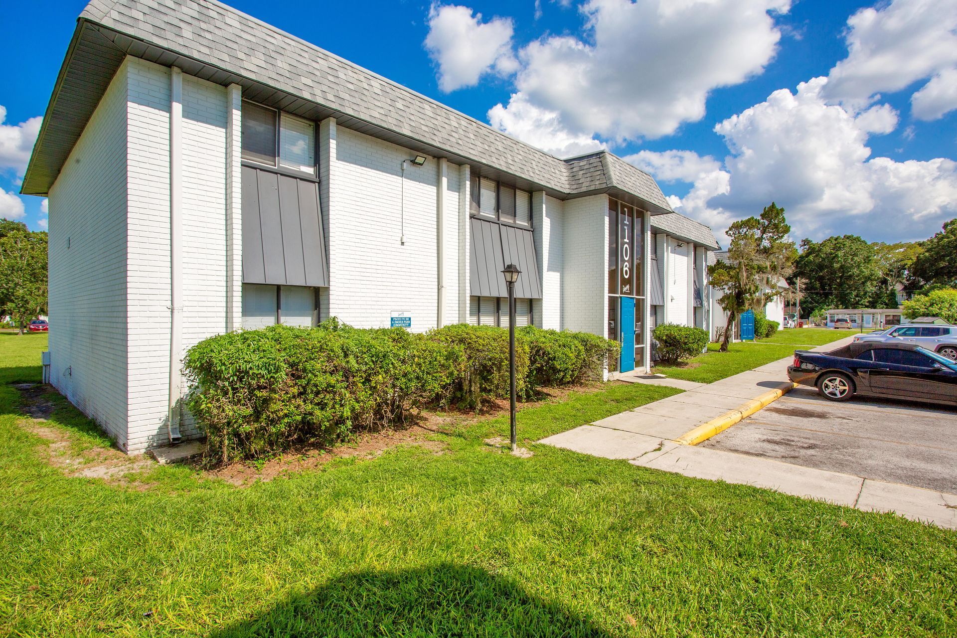A white apartment building with a car parked in front of it.