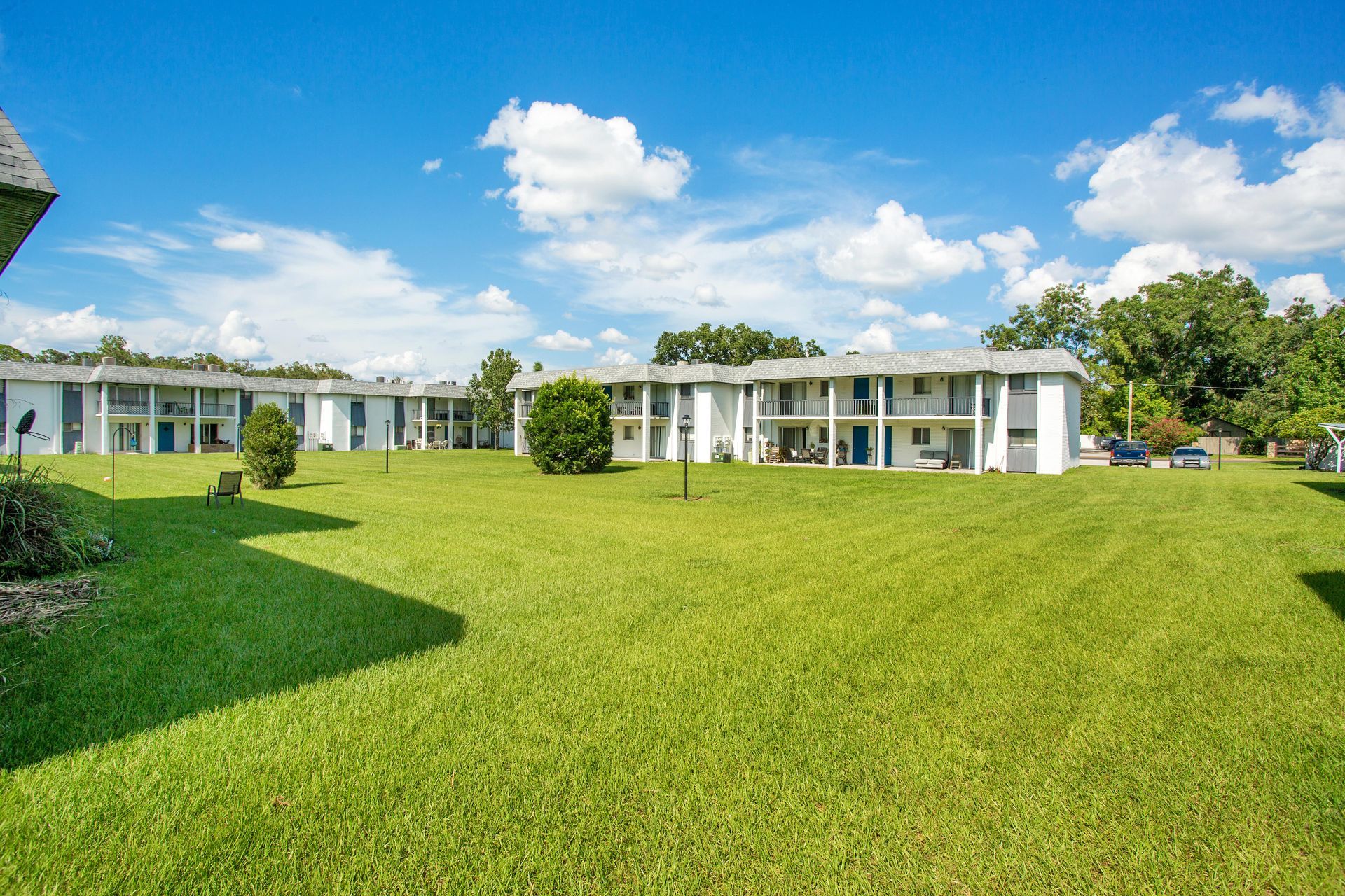 A large lush green field in front of a row of apartment buildings.