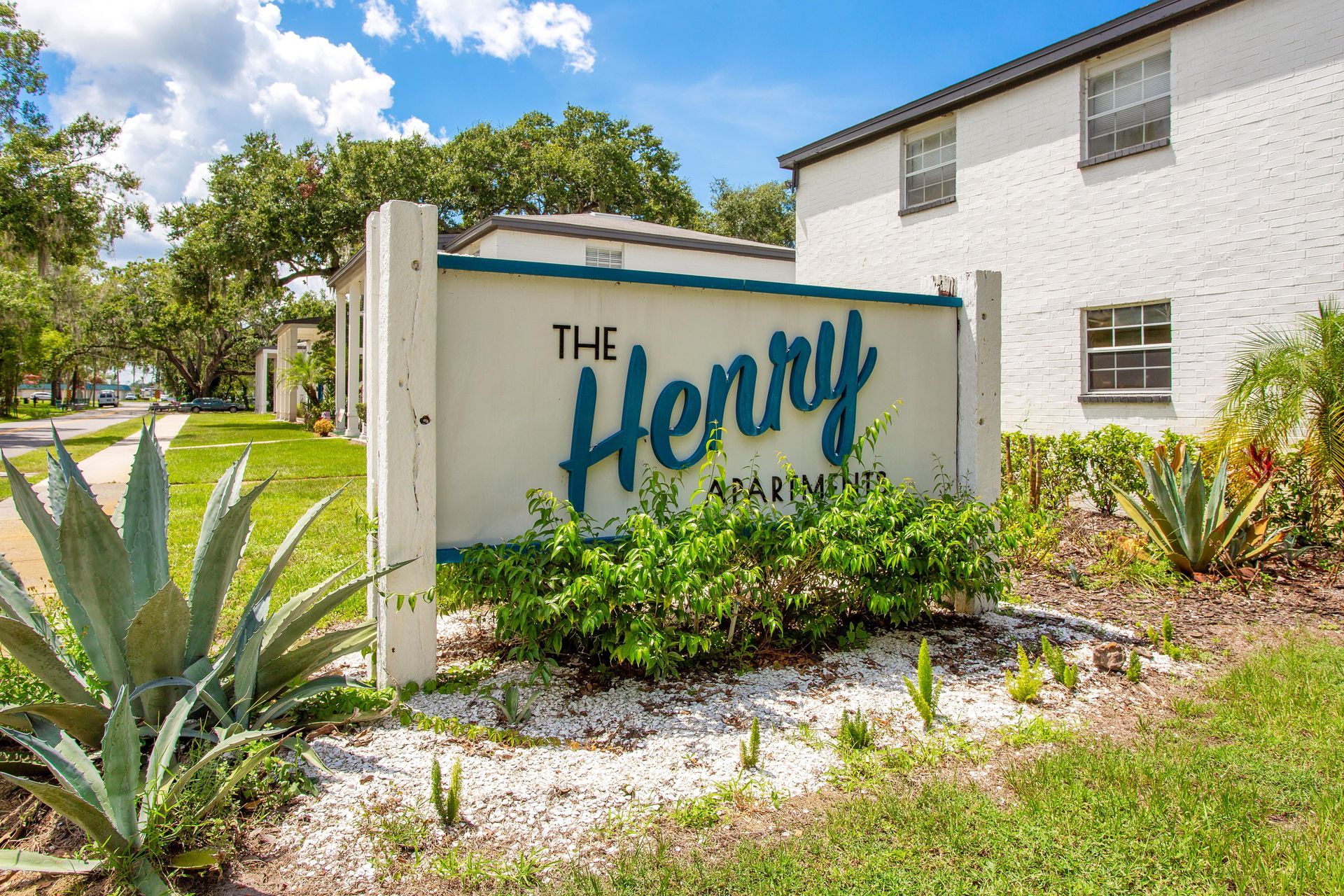 A sign for the henry apartment complex is in front of a white building.