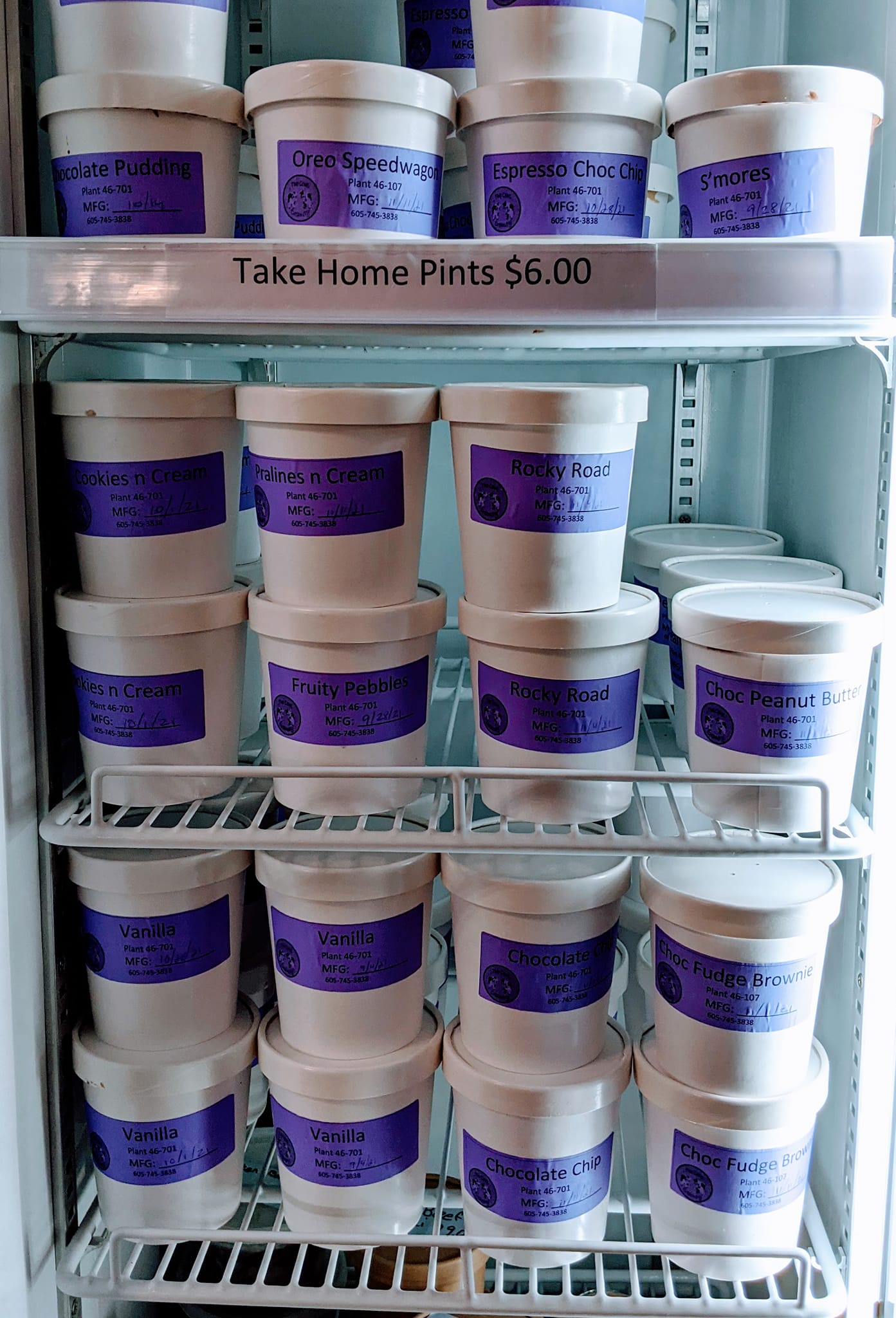 A refrigerator filled with lots of ice cream cups with purple labels.