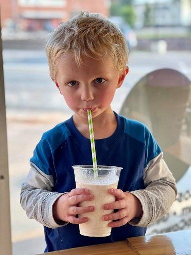 A young boy is drinking a milkshake through a straw.
