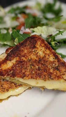 A close up of a grilled cheese sandwich on a plate with a salad.